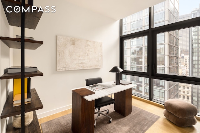 home office featuring floor to ceiling windows, baseboards, and wood finished floors