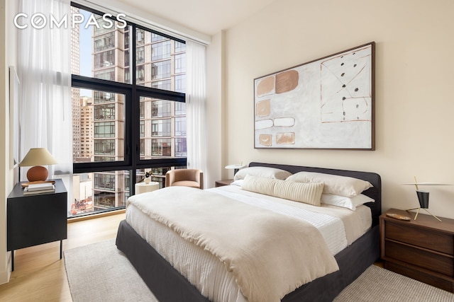 bedroom featuring light wood-type flooring and floor to ceiling windows