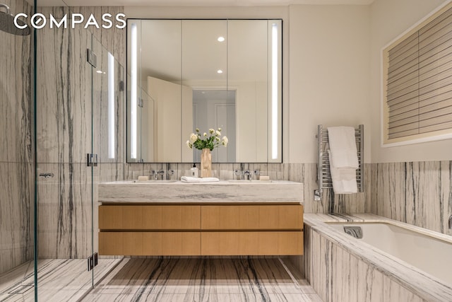 full bathroom featuring radiator, a garden tub, a shower stall, and double vanity