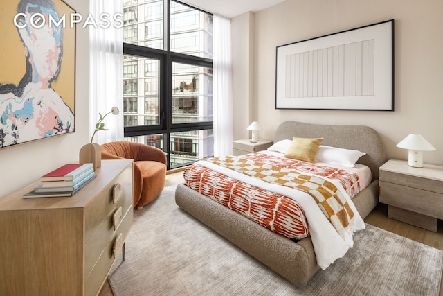 bedroom featuring expansive windows and light wood finished floors