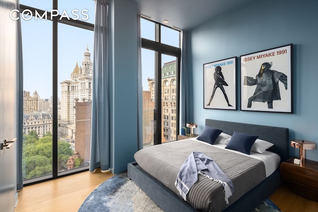 bedroom with light wood-style floors, floor to ceiling windows, a city view, and multiple windows