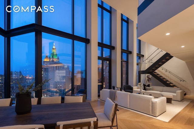 unfurnished dining area with expansive windows, stairway, parquet flooring, and a towering ceiling