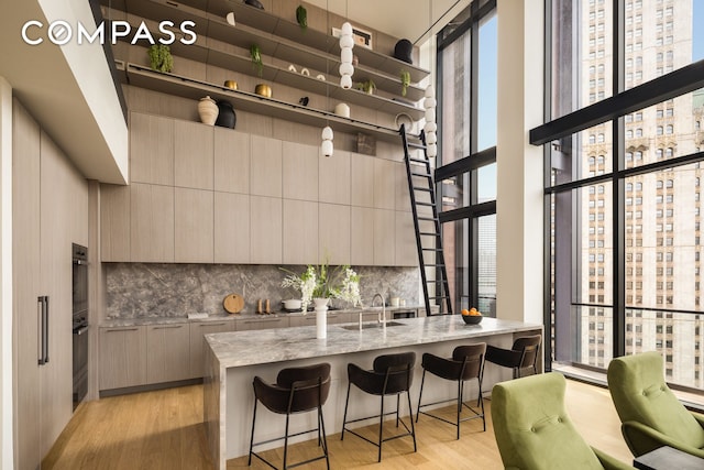 kitchen featuring a breakfast bar area, light wood-style floors, gray cabinets, backsplash, and modern cabinets