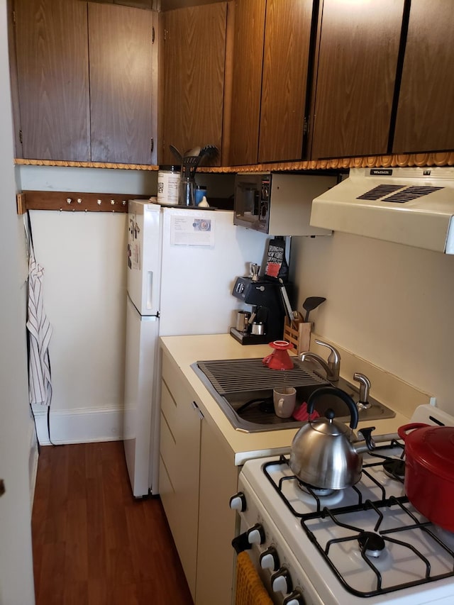 kitchen with dark wood-type flooring, a sink, light countertops, range hood, and white gas range