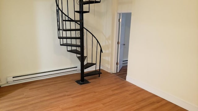 staircase featuring baseboards, baseboard heating, and wood finished floors