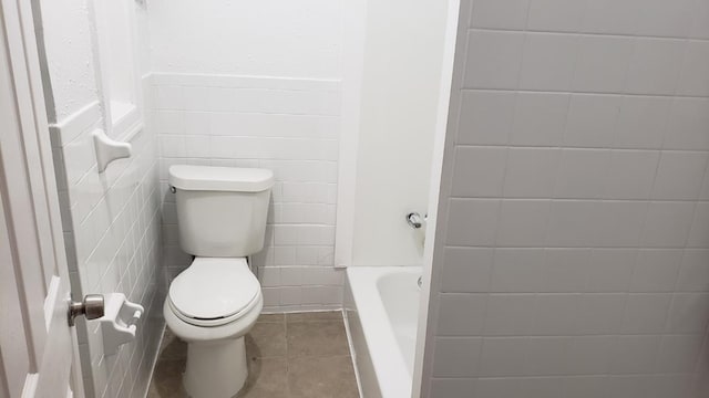 full bath featuring a tub, tile walls, toilet, and tile patterned floors