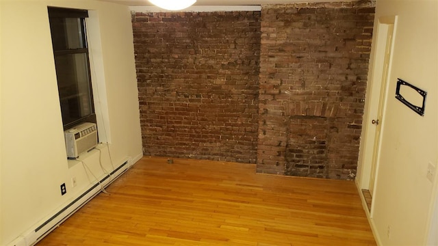 spare room featuring brick wall, light wood-style flooring, a baseboard heating unit, and cooling unit