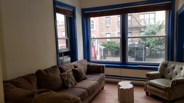 living area featuring a healthy amount of sunlight, baseboard heating, and wood finished floors