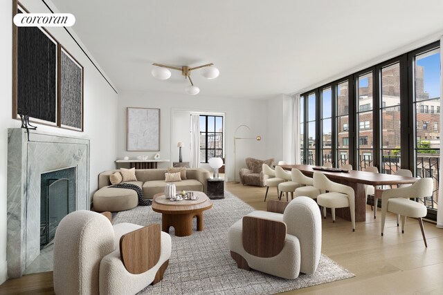 living room featuring a premium fireplace, a healthy amount of sunlight, a wall of windows, and light hardwood / wood-style flooring