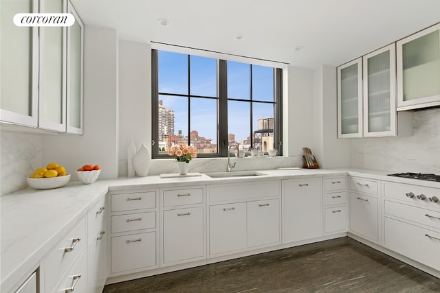 kitchen featuring sink, light stone counters, white cabinets, and backsplash