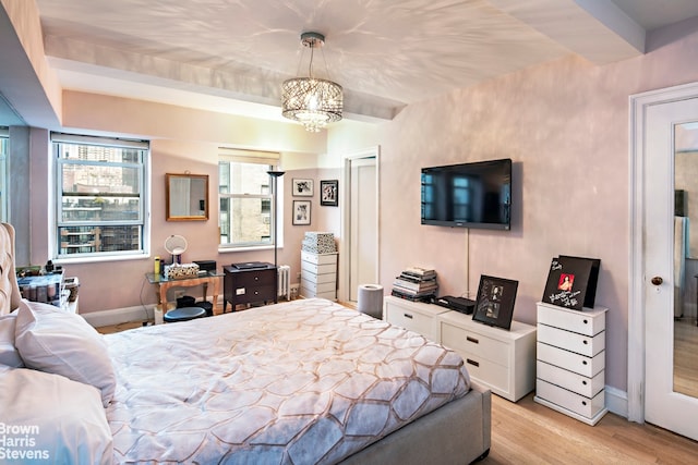 bedroom with baseboards, light wood finished floors, and a notable chandelier