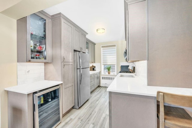 9201 Shore Rd Unit C702/703, New York City, NY 11209 - kitchen with beverage cooler, freestanding refrigerator, radiator, light wood finished floors, and backsplash