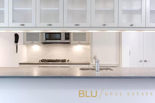 kitchen featuring decorative backsplash, sink, white cabinets, and stainless steel appliances