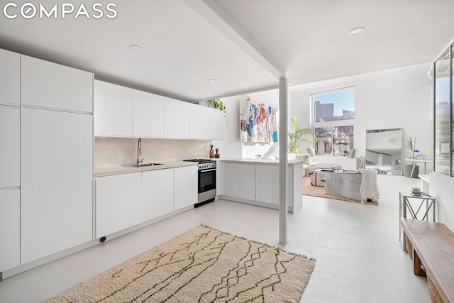 kitchen with tasteful backsplash, sink, gas stove, and white cabinetry