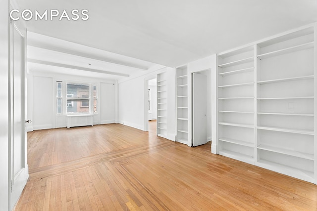 unfurnished living room featuring radiator and light wood-type flooring