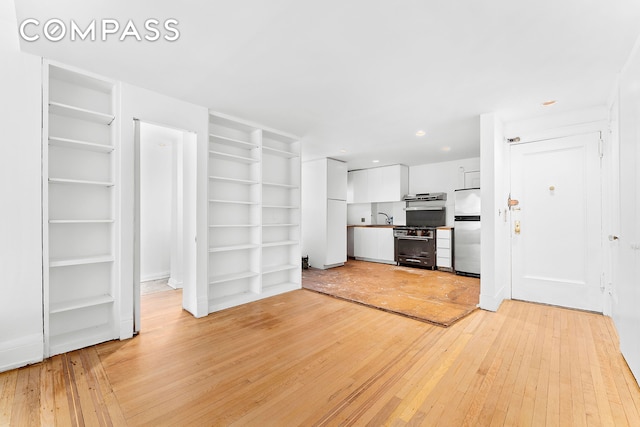 kitchen with modern cabinets, a sink, freestanding refrigerator, light wood-style floors, and white cabinets