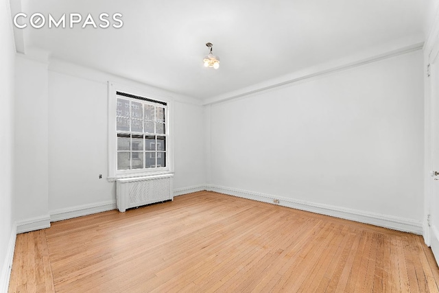 unfurnished room featuring radiator and hardwood / wood-style floors