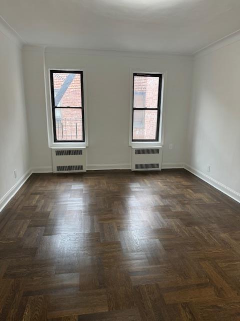 spare room with dark parquet flooring and radiator heating unit