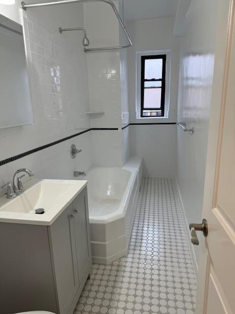 full bathroom featuring vanity and tile walls