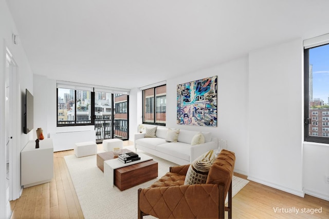 living room with a wealth of natural light, light hardwood / wood-style floors, and a wall of windows