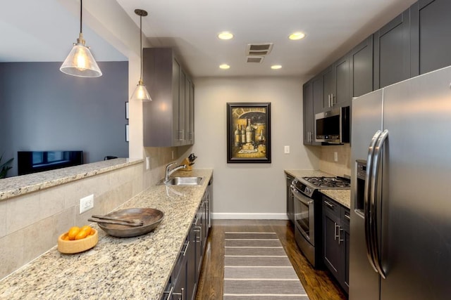 kitchen featuring light stone countertops, appliances with stainless steel finishes, pendant lighting, and decorative backsplash