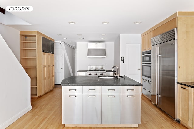 kitchen with a center island with sink, stainless steel appliances, white cabinets, light hardwood / wood-style flooring, and sink