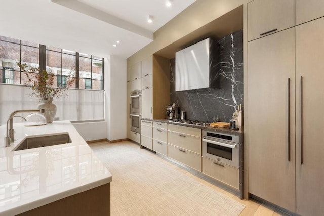 kitchen featuring appliances with stainless steel finishes, wall chimney range hood, cream cabinets, and sink