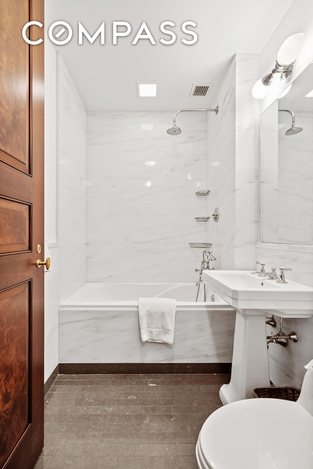 full bathroom featuring toilet, bathtub / shower combination, visible vents, and tile walls