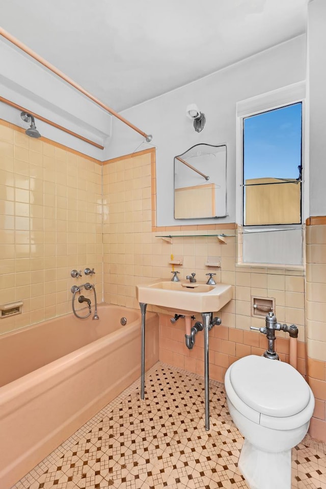 full bath featuring washtub / shower combination, toilet, and tile walls