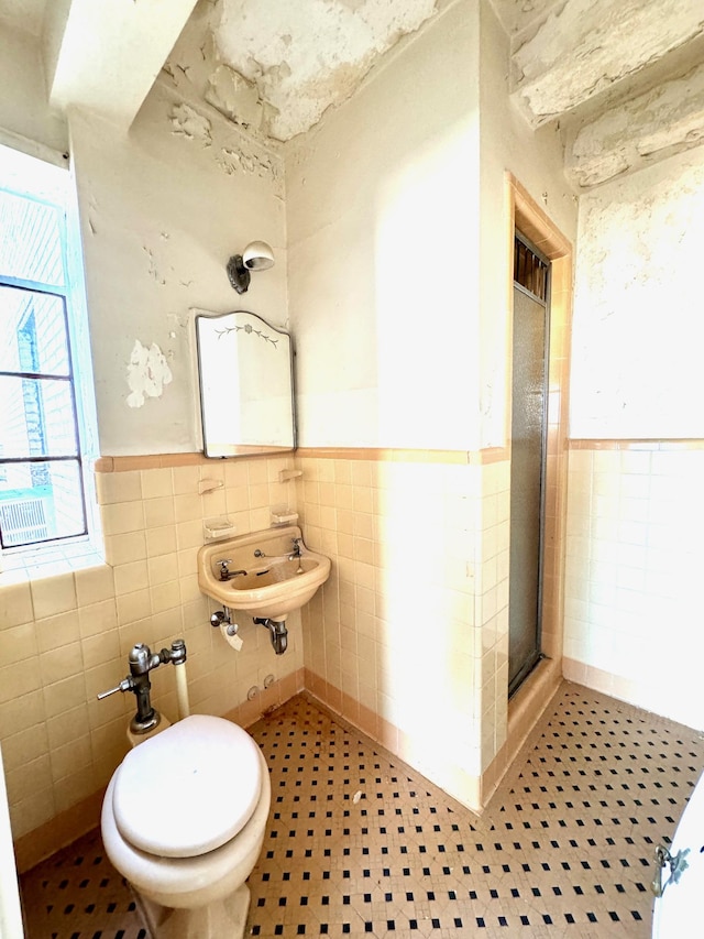 bathroom featuring a sink, tile walls, a wainscoted wall, and a shower stall