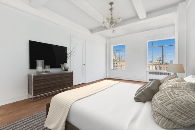bedroom featuring radiator, baseboards, beamed ceiling, and wood finished floors