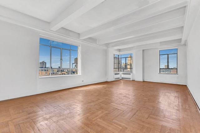 spare room featuring baseboards, a city view, and beam ceiling