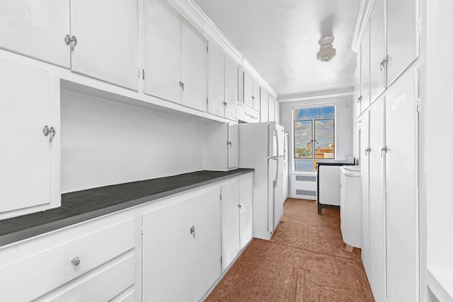 kitchen featuring dark countertops, white cabinets, freestanding refrigerator, dark colored carpet, and radiator