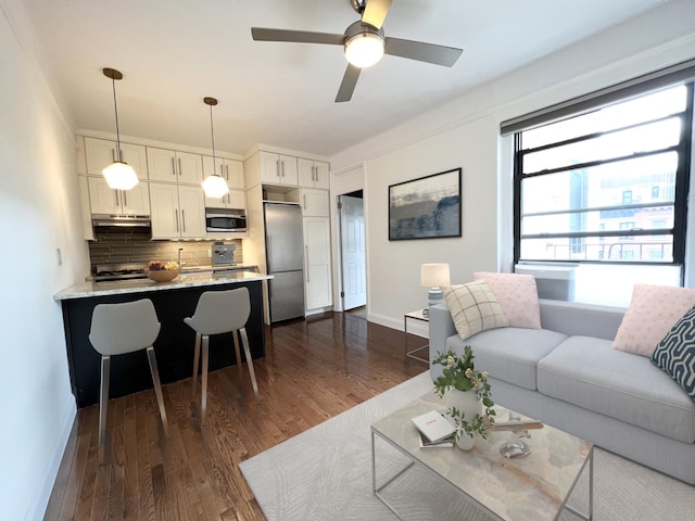 living area with ceiling fan, baseboards, and dark wood-type flooring