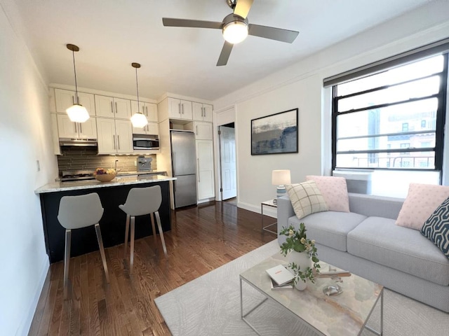 living room featuring dark wood-type flooring and ceiling fan