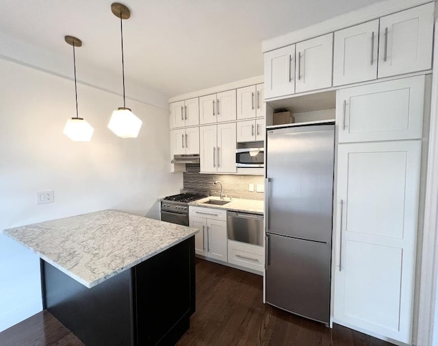 kitchen with tasteful backsplash, decorative light fixtures, high end appliances, white cabinets, and sink