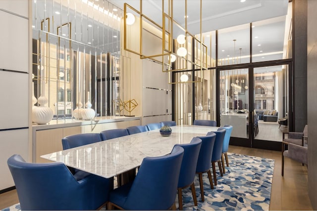 dining space featuring wood finished floors, french doors, recessed lighting, a chandelier, and a towering ceiling