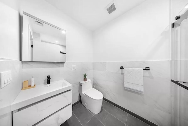 bathroom with toilet, vanity, visible vents, tile walls, and tile patterned floors