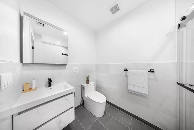 bathroom with tile walls, toilet, vanity, and wainscoting