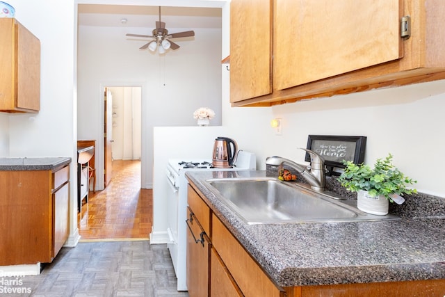 kitchen featuring sink, white gas range oven, ceiling fan, and dark parquet floors