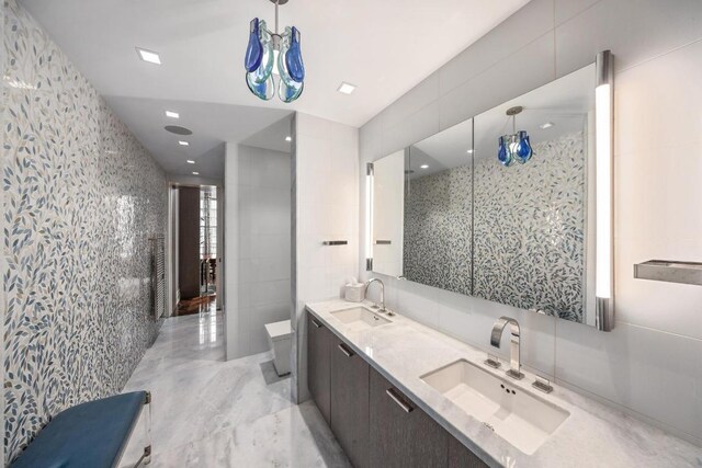 bathroom with vanity, a shower with shower door, tile walls, and toilet