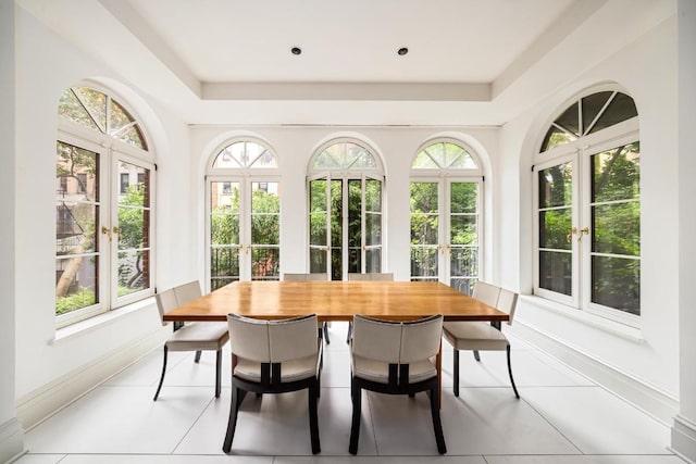 sunroom featuring a raised ceiling, plenty of natural light, and french doors