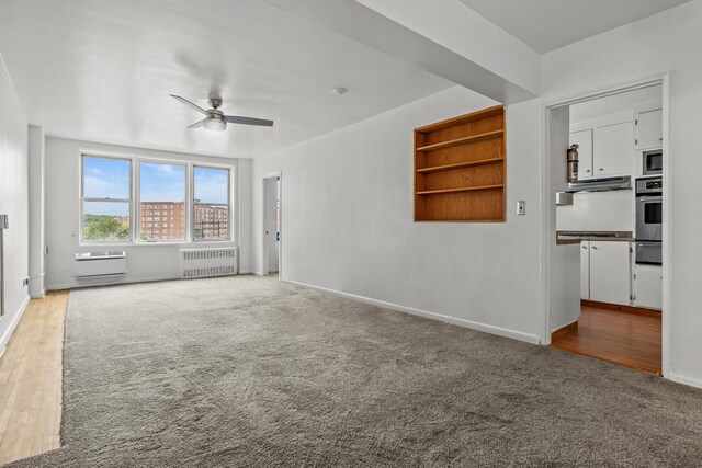 unfurnished living room featuring ceiling fan, light colored carpet, and radiator heating unit