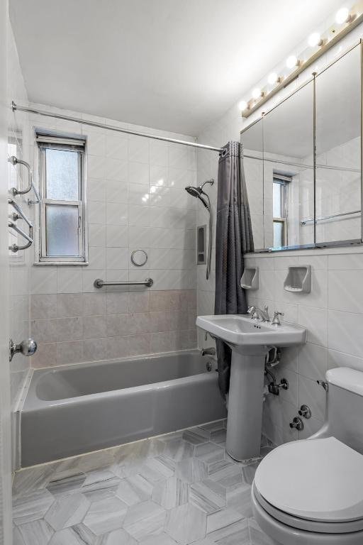 bathroom featuring toilet, tile walls, and shower / tub combo