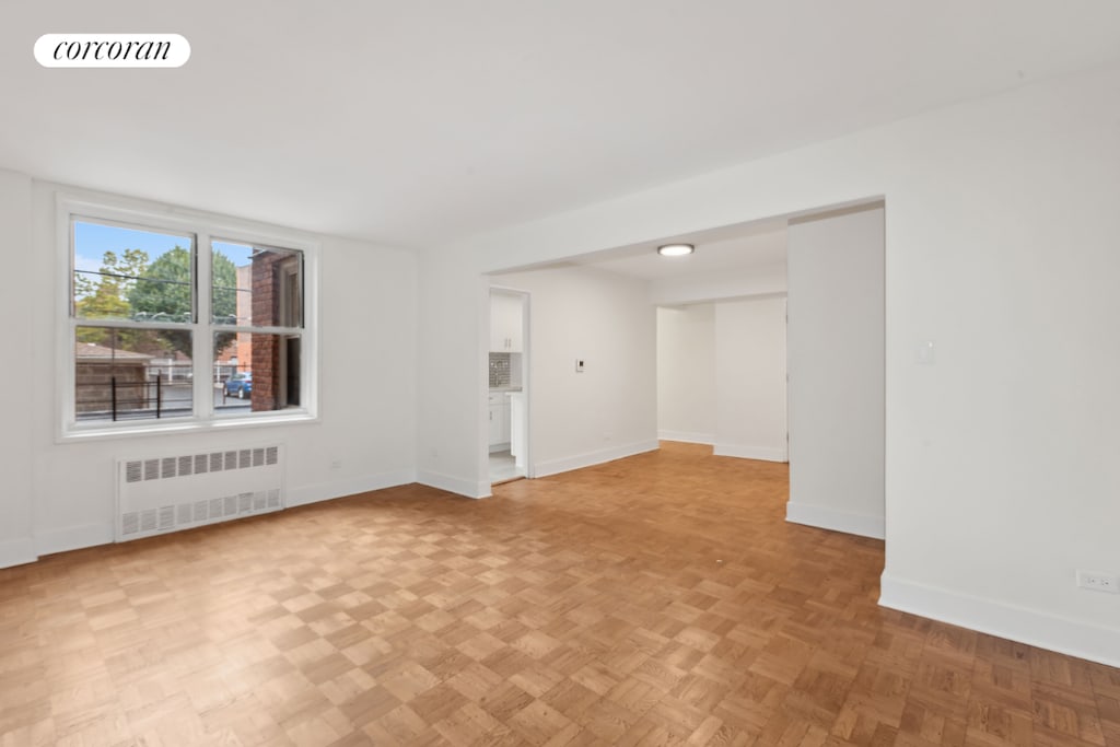 spare room with radiator heating unit and light parquet floors