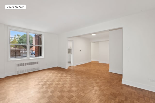 spare room with radiator heating unit and light parquet floors