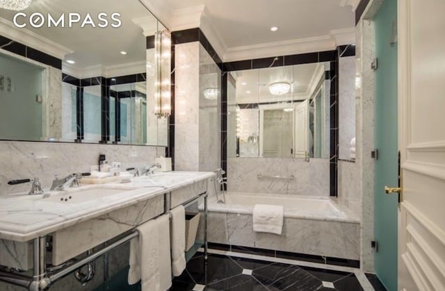 bathroom featuring crown molding, double vanity, a bath, tile walls, and a sink