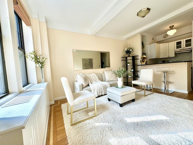 living room with baseboards, beam ceiling, and wood finished floors