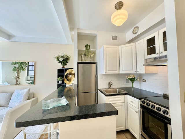 kitchen featuring visible vents, under cabinet range hood, electric range oven, freestanding refrigerator, and a sink