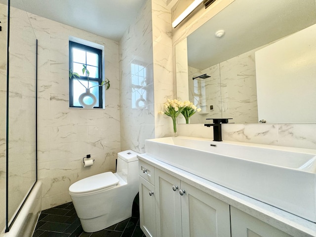 bathroom featuring tile patterned flooring, toilet, vanity, combined bath / shower with glass door, and tile walls